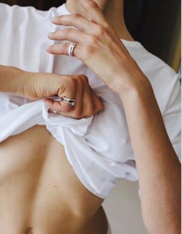 Hands with stacked silver rings holding a white shirt