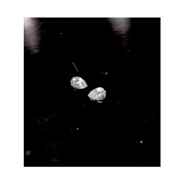 Two pear-cut diamonds on a dark surface